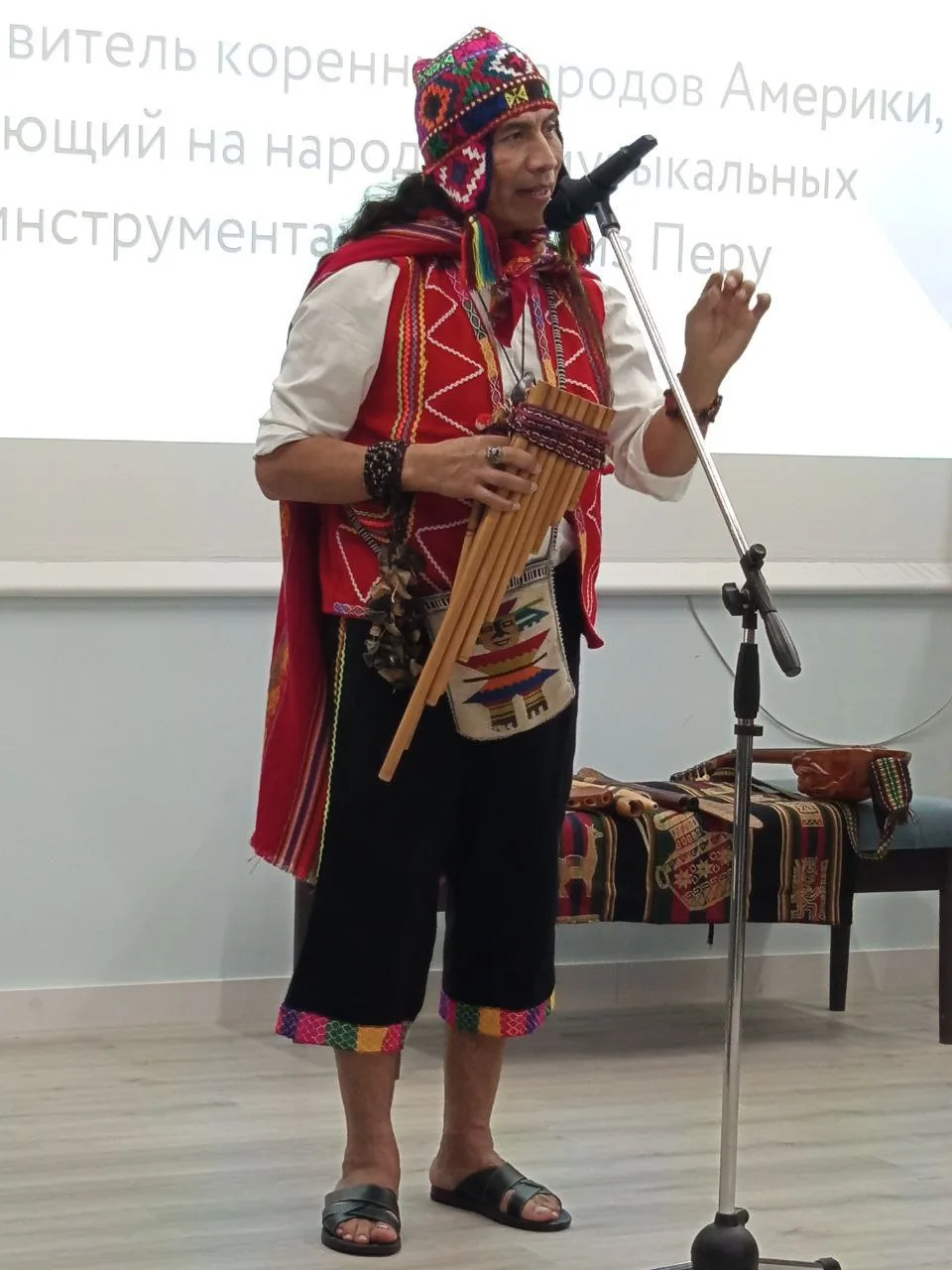 Robert Mamani actúa con flauta de pan en un poncho rojo